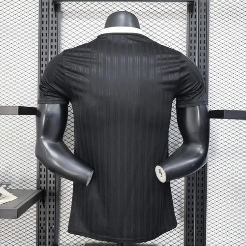 Jersey de fútbol negro con patrón rayado mostrado en modelo, ideal para los fans de PSG o Real Madrid